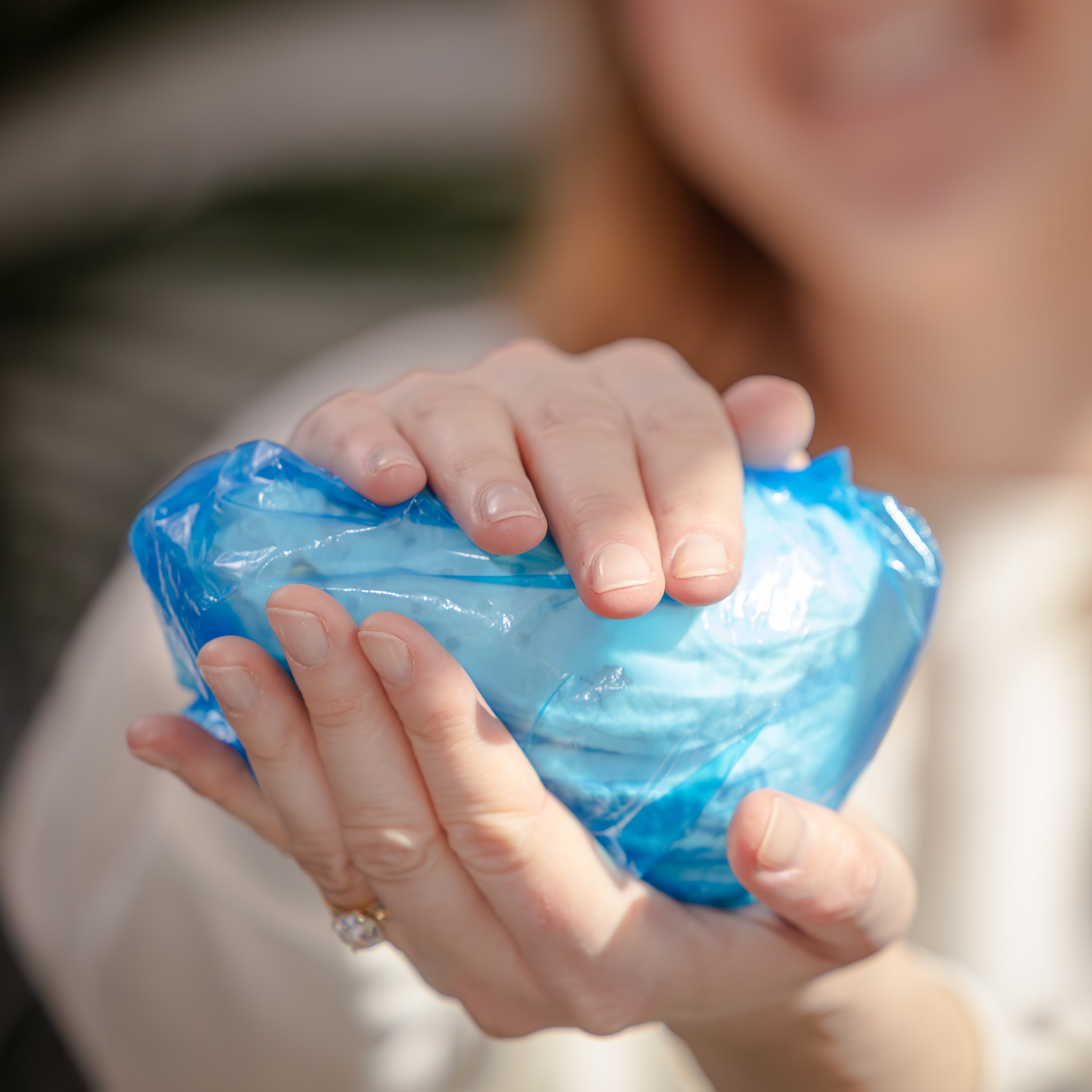 Person holding a fully sealed diaper in a DiaperSealer bag. Blurred background.