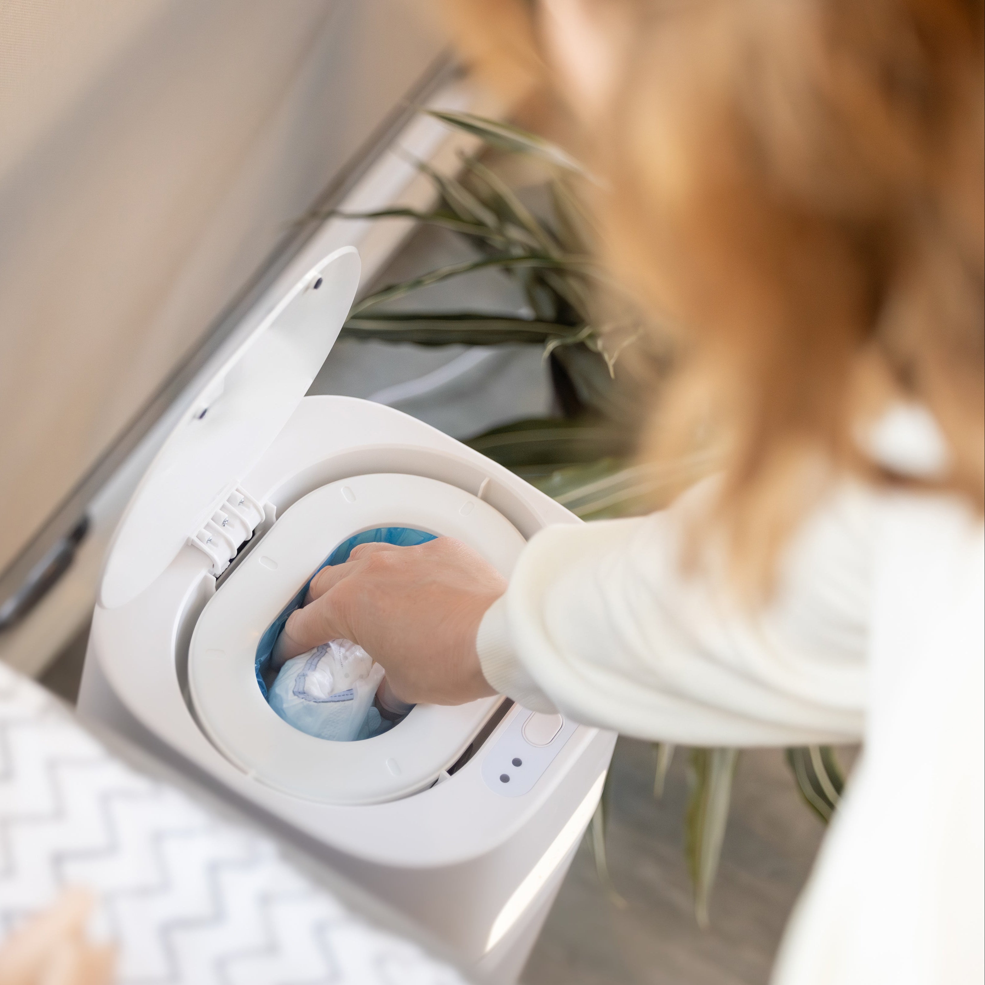 Person disposing of a used diaper in DiaperSealer canister.