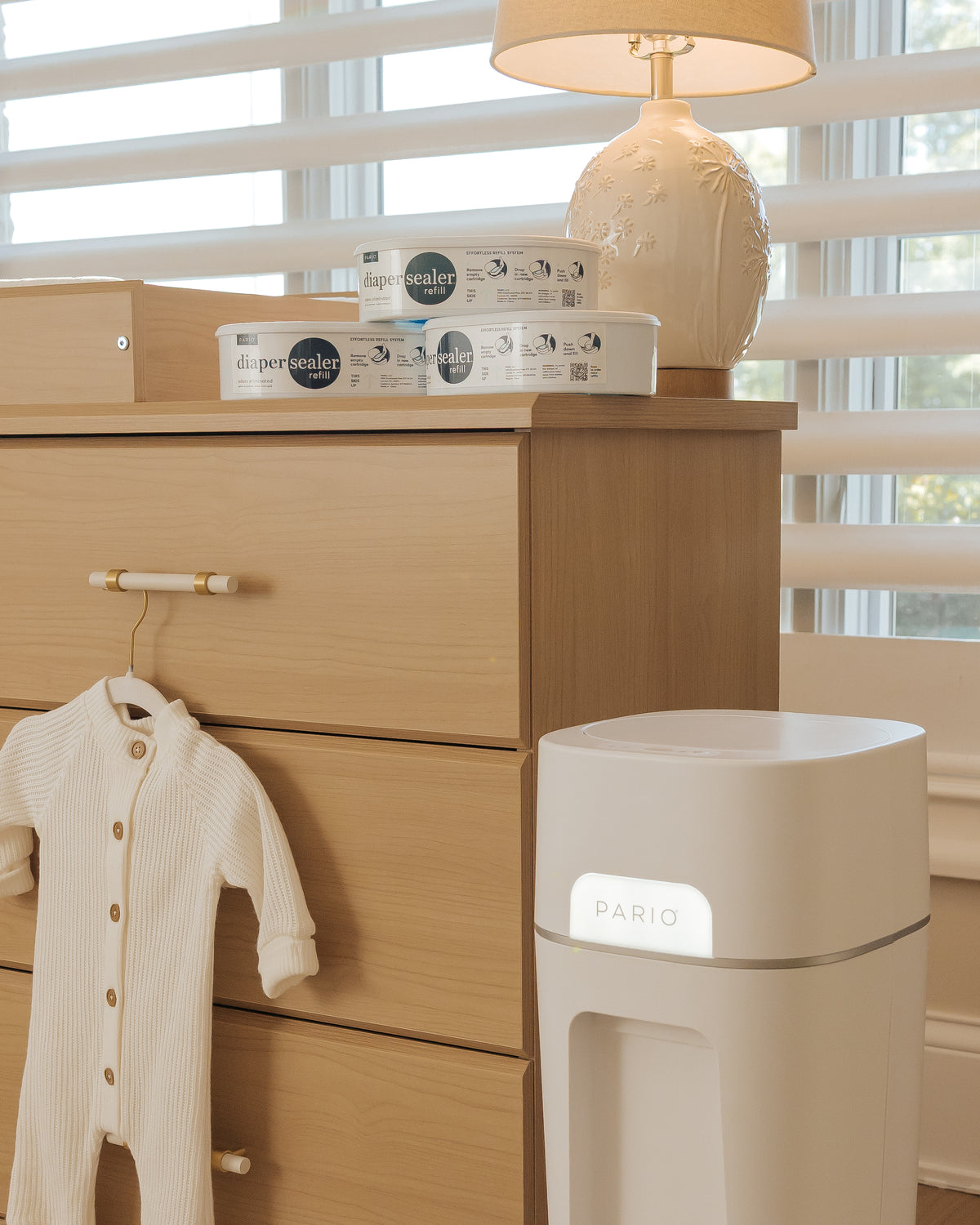 Baby onesie on a wooden dresser with a DiaperSealer in the foreground.