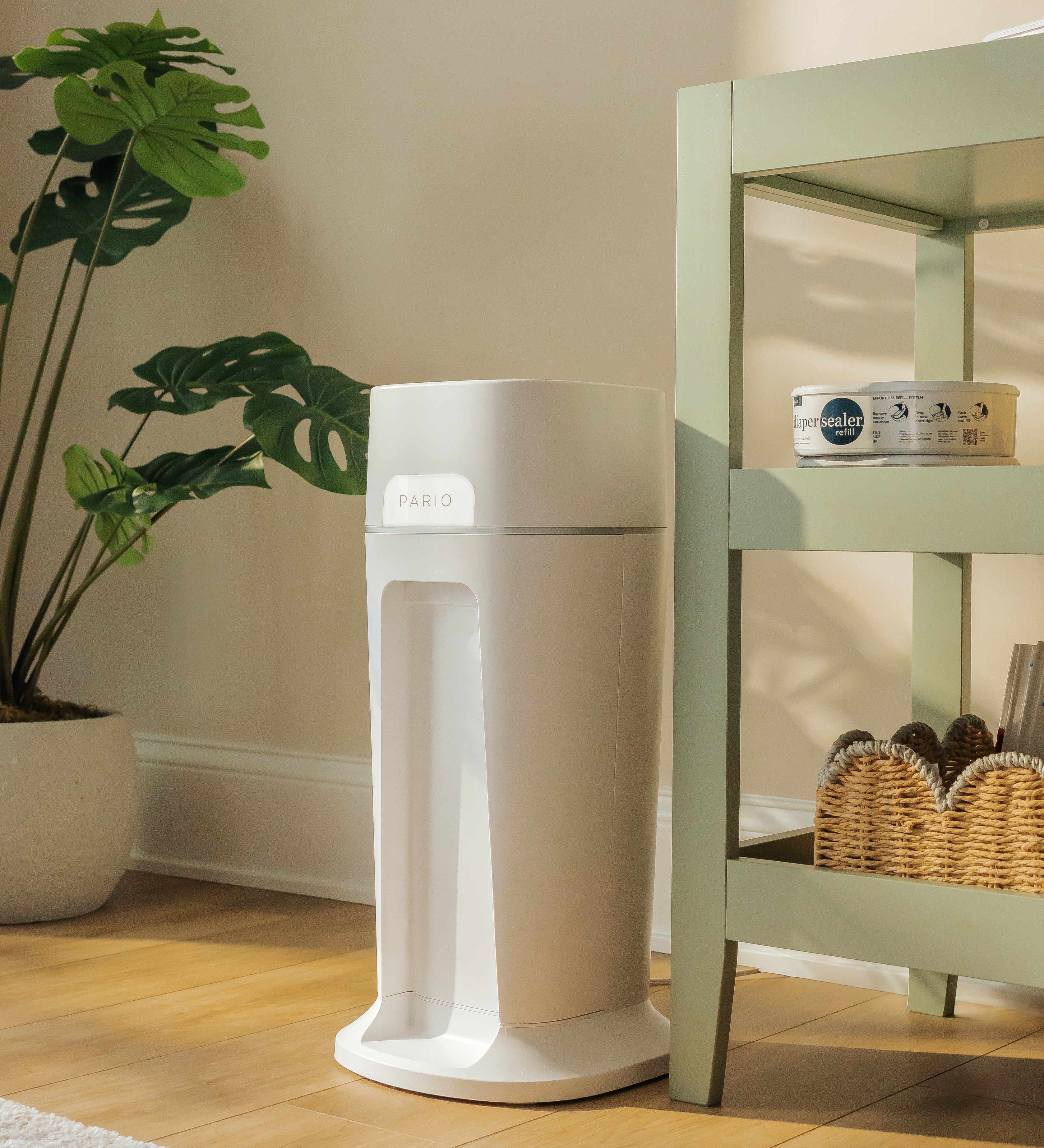 DiaperSealer product on a wooden floor with a plant and shelf in the background