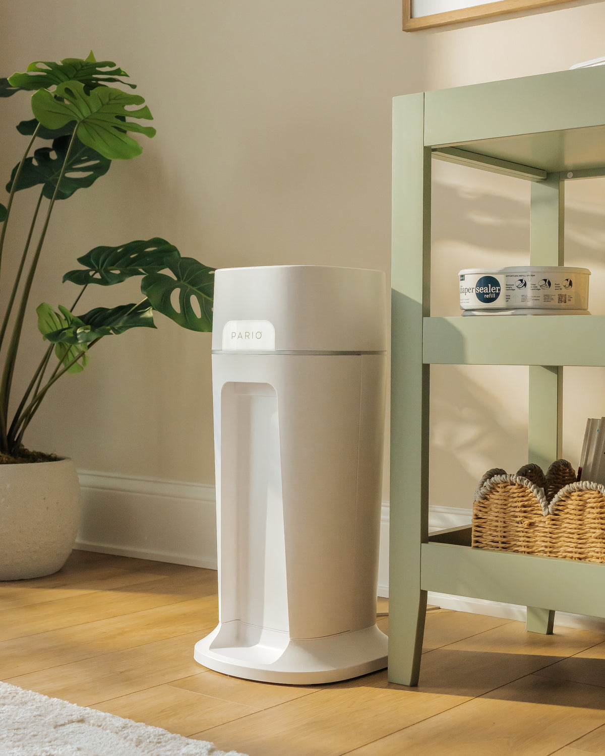 DiaperSealer product on a wooden floor with a plant and shelf in the background