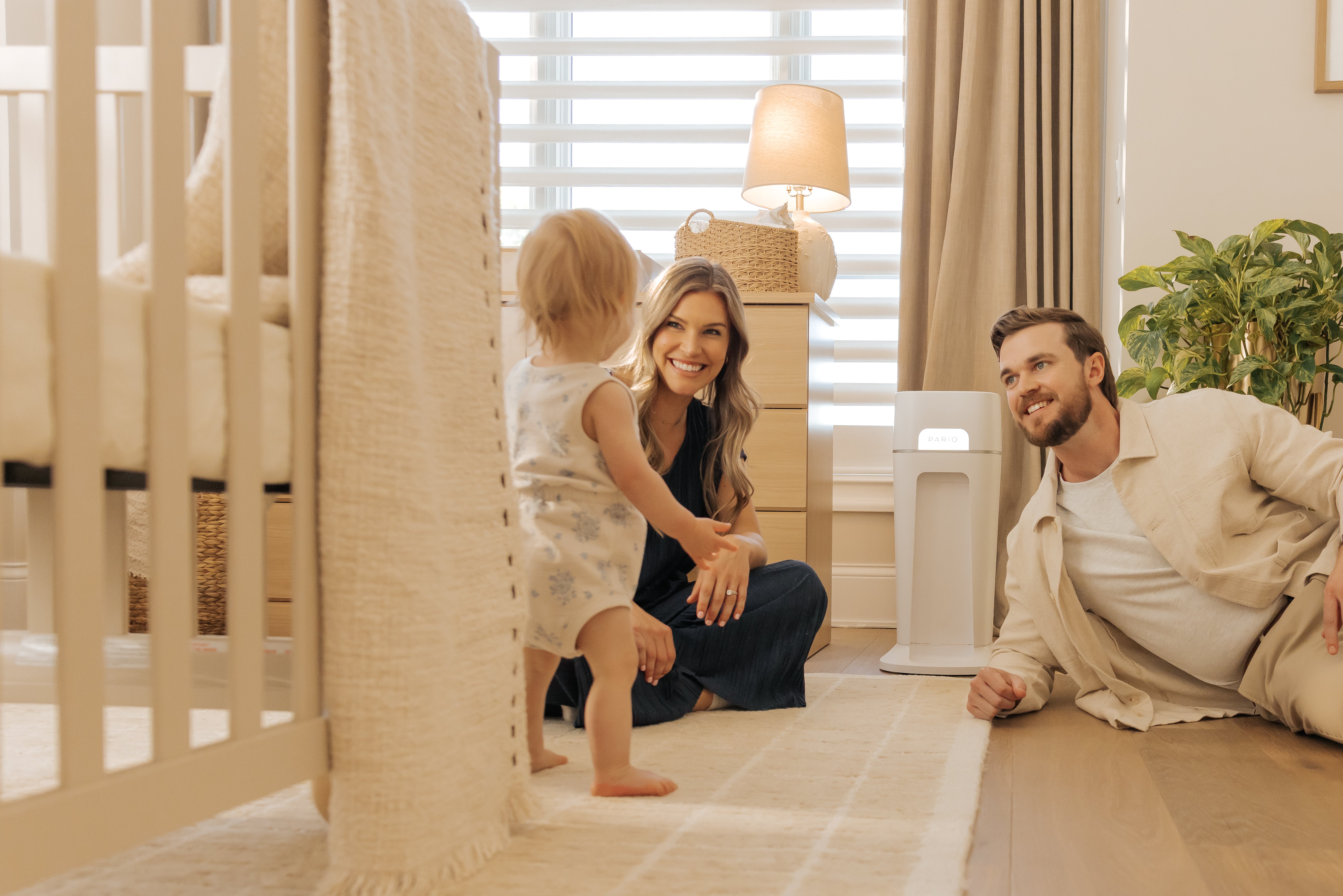 Woman and man, smiling and interacting with their baby. DiaperSealer in the background.